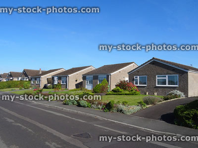 Stock image of bungalows in row on housing estate, by tarmac-road
