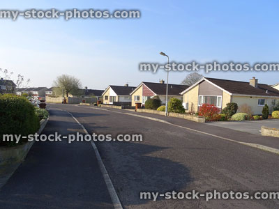 Stock image of single storey bungalow homes on tarmac road, housing estate