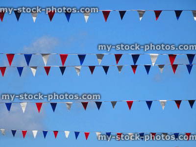 Stock image of bunting flags in rows against blue sky background