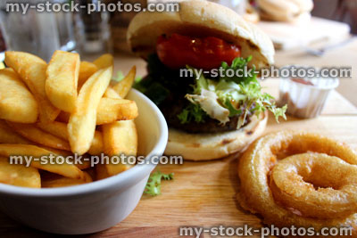 Stock image of gourmet burger, chunky chips, onion rings and salad
