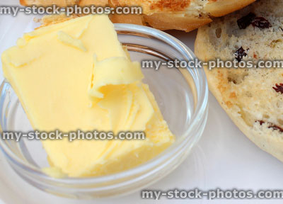Stock image of toasted teacakes on white plate, butter in glass dish