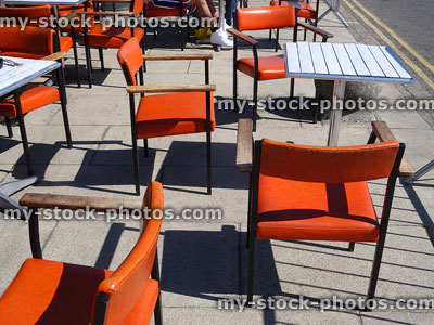 Stock image of outside cafe tables and orange chairs on pavement