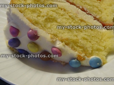 Stock image of slice of sponge cake , cream / jam, decorated with icing, chocolate sweets