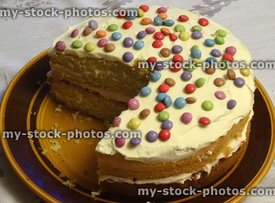 Stock image of homemade sponge cake with cream / jam, decorated with icing, chocolate sweets