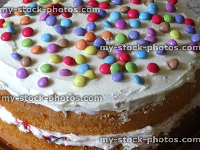 Stock image of homemade sponge cake with cream / jam, decorated with icing, chocolate sweets