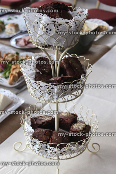 Stock image of homemade chocolate brownies on three tier cake stand, edible glitter, paper doily