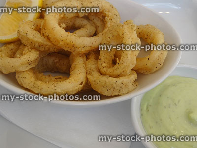 Stock image of fried, battered calamari rings with lemon and mayonnaise
