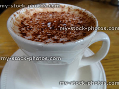 Stock image of white mug frothy coffee, cappuccino coffee cup, dusted with cocoa / chocolate powder