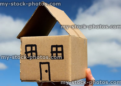 Stock image of cardboard dolls house in hands, against blue sky