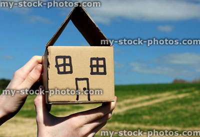 Stock image of cardboard dolls house being held in hands, against sky 
