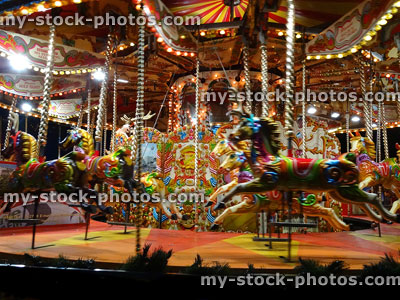 Stock image of moving carousel roundabout with lights, painted / decorated horses