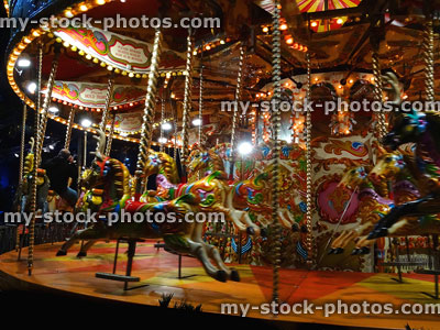 Stock image of carousel roundabout at night time, with wooden horses, light bulbs