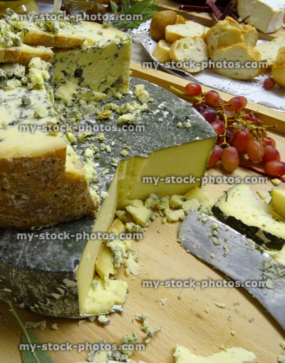 Stock image of stack of cheeses / Blue Stilton, Cornish Yarg cheese cake on wooden board