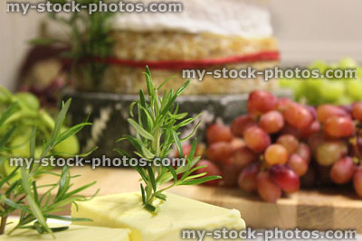 Stock image of stack of cheeses / cheese cake, wooden board, seedless grapes, butter