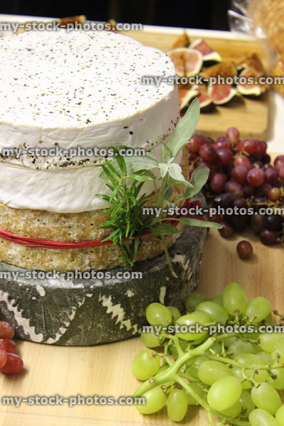 Stock image of stack of cheeses / cheese cake, wooden board, grapes