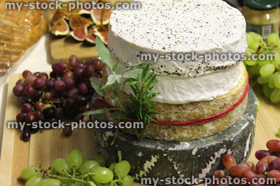 Stock image of stack of cheeses / cheese cake, wooden board, grapes