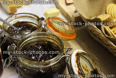 Stock image of jars of homemade chutneys and pickles, next to cheese board