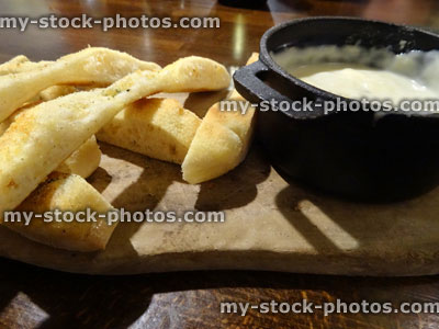 Stock image of melted cheese fondue on wooden board, focaccia bread
