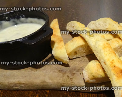 Stock image of melted cheese fondue on wooden board, focaccia bread