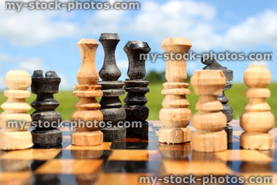 Stock image of chessboard game / wooden chess set against sky, boardgame (close up)