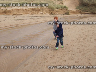 Stock image of young children walking on beach, next to stream