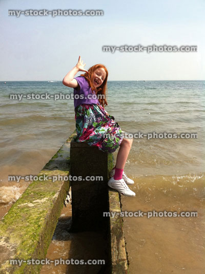Stock image of girl sitting on beach groyne next to sea