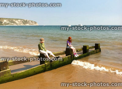 Stock image of children sitting on beach groyne next to sea