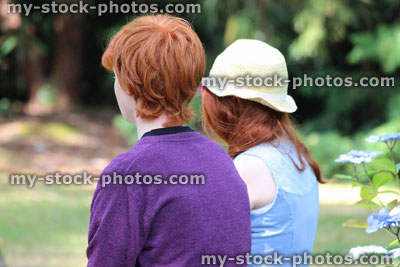 Stock image of boy and girl sitting on bench (brother sisiter), woodland garden