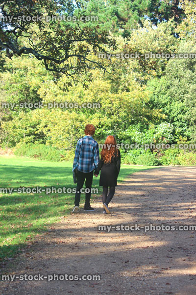 Stock image of boy and girl walking along woodland pathway / footpath, holding hands, red hair