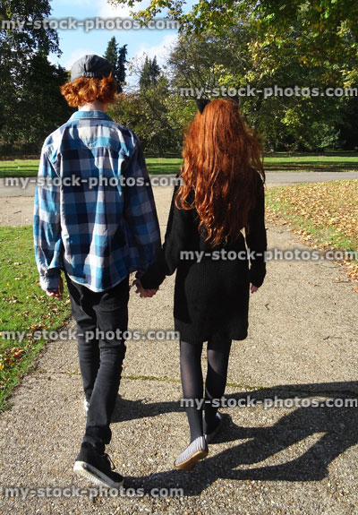 Stock image of boy and girl walking along woodland pathway / footpath, holding hands, red hair