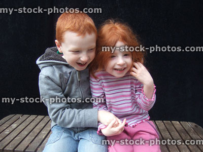 Stock image of affectionate young children giggling, smiling, tickling each other