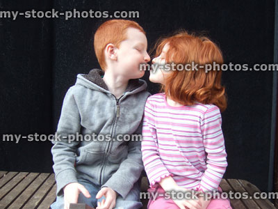 Stock image of young loving red haired children kissing as they pose