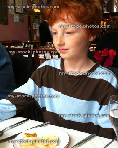 Stock image of red haired boy eating poppadoms in an Indian Restaurant