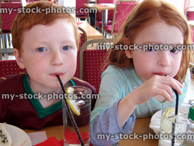 Stock image of young children in restaurant drinking glass of lemonade