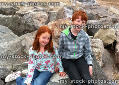 Stock image of boy and girl sitting on rocks at beach