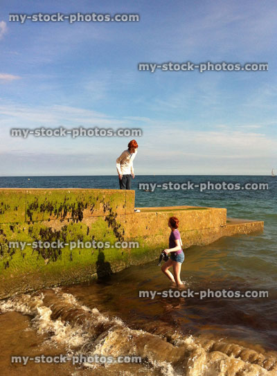 Stock image of boy and girl playing with seaweed on beach sea groyne 