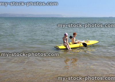 Stock image of children at beach, yellow sea kayak, water sports