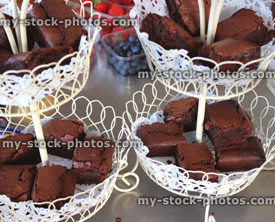 Stock image of homemade chocolate brownies on three tier cake stand, edible glitter, paper doily