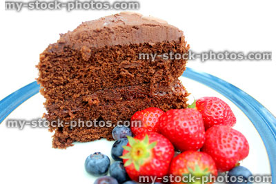 Stock image of rich chocolate cake, served with strawberries and blueberries