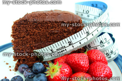 Stock image of tape measure with chocolate cake, strawberries and blueberries