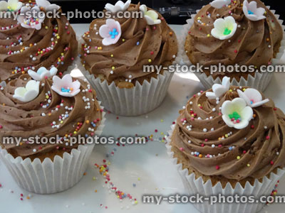 Stock image of chocolate cupcakes decorated with piped icing, sugarcraft flowers