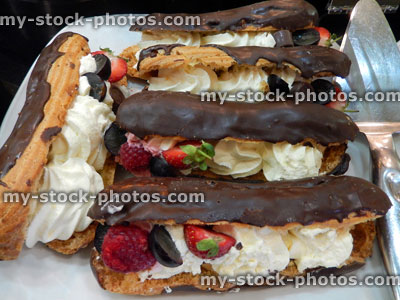 Stock image of chocolate and cream eclairs, with strawberries, cream cakes