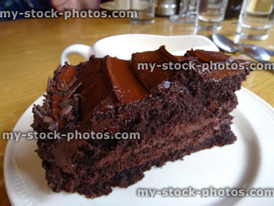 Stock image of homemade chocolate fudge cake slice, jug of cream, ganache butter icing