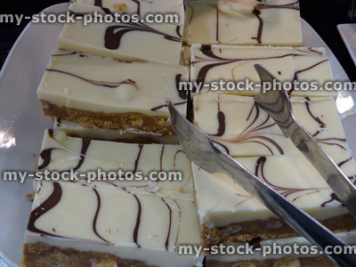 Stock image of freshly baked vanilla cake slices, striped chocolate icing / kitchen tongs