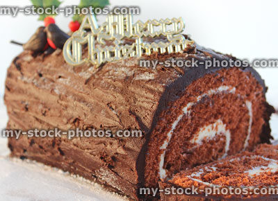 Stock image of Christmas chocolate log cake sliced, decorated with ganache icing