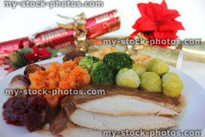 Stock image of Christmas dinner with crackers, roast turkey, vegetables, cranberry sauce