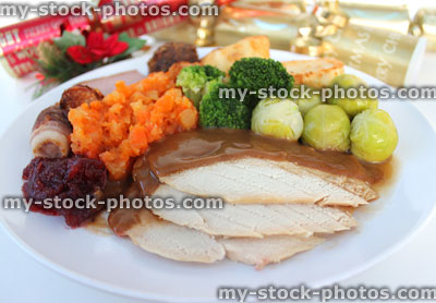 Stock image of sliced turkey on Christmas dinner plate, sprouts, crackers
