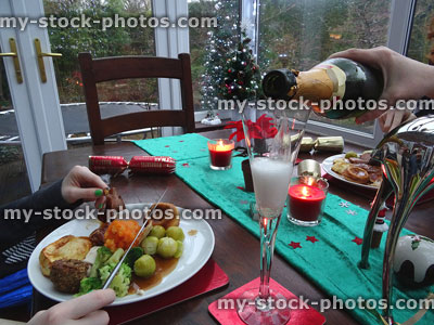 Stock image of pouring champagne at Christmas dinner, candles, crackers, decorations