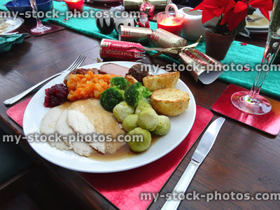 Stock image of roast dinner on decorated Christmas dining table, crackers