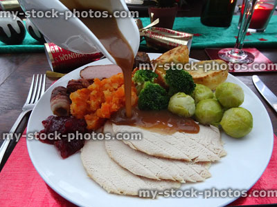 Stock image of gravy jug pouring over Christmas dinner meat / vegetables